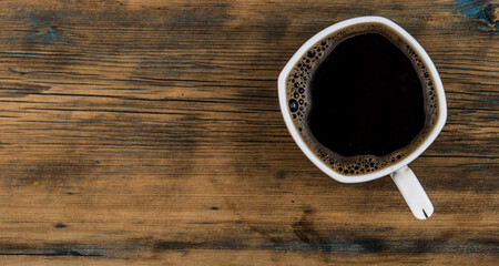 Cup of coffee on wooden table, top view