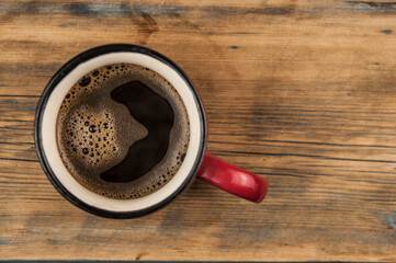 Cup of coffee on wooden table, top view