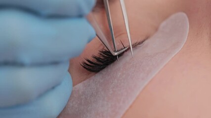 Eyelash extension procedure. The working process of professional beauty master lengthening female lashes. Fake eyelashes. Eyelashes extensions close up. Makeup artist and client in beauty salon