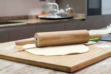 Detalle de una masa de pizza casera junto a un rodillo en la encimera de la cocina. Hacer pan en casa concepto