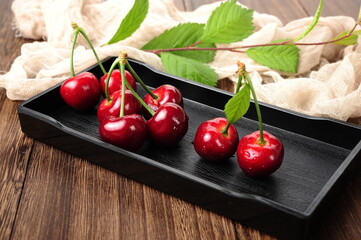 Fresh cherry fruit and leaf on wooden table.