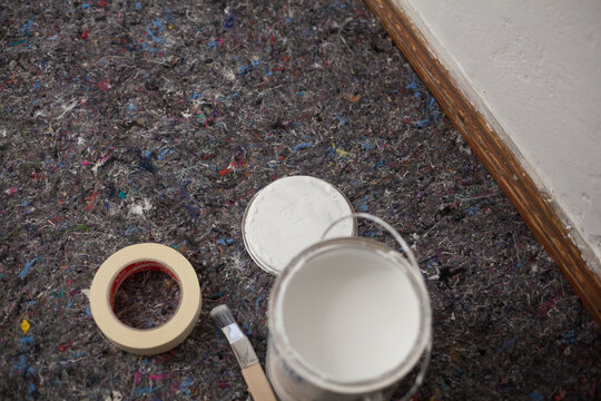 Paint buckets and painting accessories are laid out on painted fleece ready for painting the walls brush and masking tape drip protection paint blobs specialist knowledge preparation renovation tool