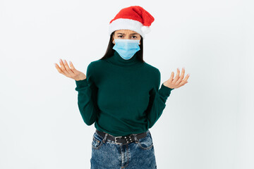Fototapeta na wymiar Displeased frustrated young woman wearing red Santa hat and medical mask to protect against virus