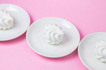 White marshmallow on a pink background. White marshmallow on a white plate. Light dessert