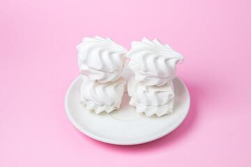 White marshmallow on a pink background. White marshmallow on a white plate. Light dessert