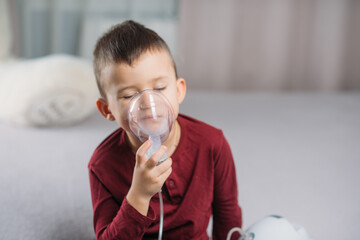 the child sitting on the bed in the bedroom makes an inhalation on their own