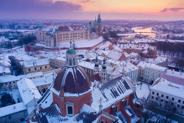 Winter in Krakow Poland old town aerial view. Saints Peter and Paul Church dome, St. Andrew's Church bell towers, and Wawel Royal Castle with Vistula river at sunset.