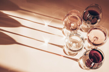 Glasses of red, rose and white wine with sunshine shadow effect. Concept of wine tasting. Flat lay, top view.