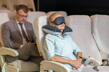 The elderly female passenger slept in a blindfold and covered a comfortable blanket on the back,...