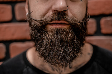 Close-up of handsome old-fashioned hipster tattooed and pierced on a brick background.