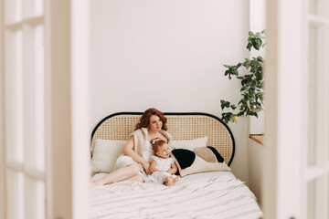 Obraz na płótnie Canvas Happy family sleepy funny cute beautiful mom and daughter small child relaxing lying on the bed Playing spending time together in a cozy bright bedroom at home, mother's day, selective focus