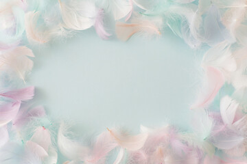 Colorful feathers on pastel blue background. Flat lay, top view, copy space