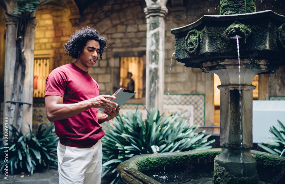Poster puzzled hispanic tourist with touch pad reading travel information on network website using 4g inter