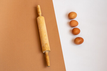 rolling pin and chicken eggs on white and beige backgrounds