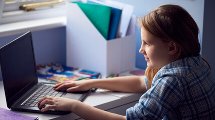 Girl Sitting At Desk Home-Schooling Using Laptop For Online Learning During Health Pandemic