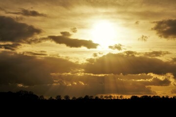 Landschaft in Nordrhein Westfalen im Winter. Bewölkter Himmel in der Abenddämmerung mit Sonnenstrahlen.