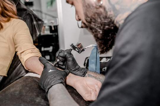 Close up of the tattoo machine. Tattooing. Man creating a picture on his hand by a professional tattoo artist