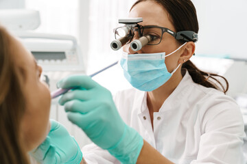 European dentist woman using microscope while working in dental clinic