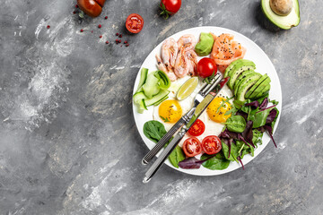 Keto breakfast for keto diet. Breakfast salmon, boiled shrimps, prawns, fried eggs, fresh salad, tomatoes, cucumbers and avocado. top view. Low carb diet concept. high fat diet