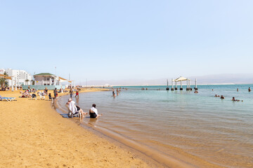 Numerous visitors relax on a comfortable beach on the coast of the Dead Sea in southern Israel
