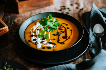 Vegetarian, homemade pumpkin cream soup in a bowl on wooden table. 