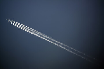jet plane flies high in the blue sky, leaving behind a jet trail