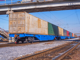 Long freight train of Idler flatcars loaded with intermodal 40-fts containers on the marshalling...
