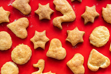 Flat lay top above view of sweet tasty delicious curd ginger cookies baked in hot oven stove on red bright silicone bakery mat at home kitchen. Homemade hot biscuits pattern background