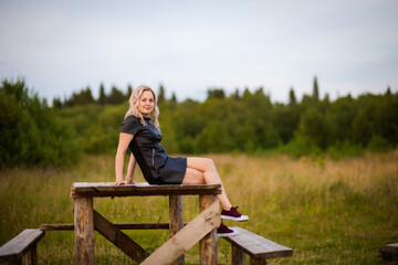 blonde girl in black dress in nature, selective focus