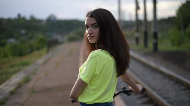 Girl with a bike: close-up. A little video of walking with a girl: firstly she is in unfocused area, then is focused; girl's face closely. 