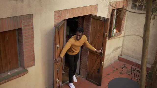 Young Black Man Closing Front Door Home. African Person Closes House Property Doors