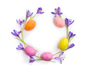 Easter decoration. Circle Easter frame of flowers violet crocuses, colored easter eggs on white background with space for text. Top view, flat lay