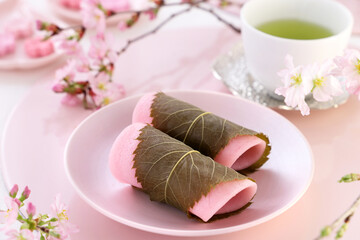 Japanese traditional sweets, 
Sakura Mochi wrapped with salted cherry leaves.
Beautiful cherry blossoms background. 桜餅　啓翁桜　おうちでお花見