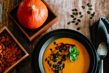 Vegetarian, homemade pumpkin cream soup in a bowl on wooden table. 