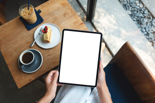 Top view mockup image of a business woman holding digital tablet with blank white desktop screen in cafe
