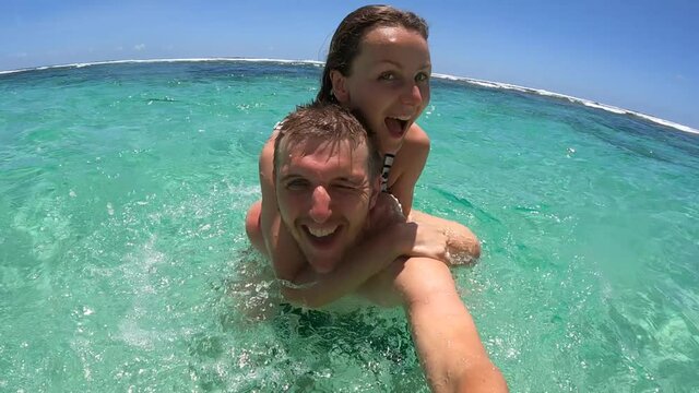 Romantic holidays concept. Young couple playing in an ocean looking to the camera