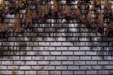 A bouquet of flowers hung on a white brick wall.