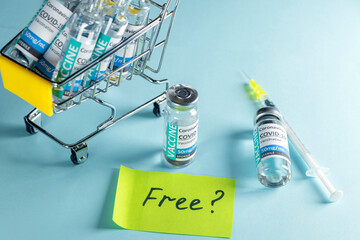 Covid-19 Corona Virus 2019-ncov vaccine vials medicine drug bottles in shopping trolley, syringe injection and note with text FREE . Vaccination, immunization