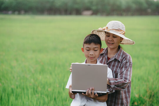 Children holding laptop and mother on rice field background