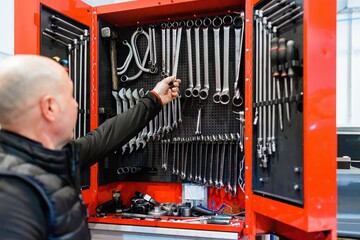Mechanic in a car repair shop picking up work tools