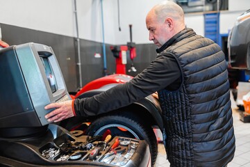 Fototapeta premium Mechanic in a car repair shop aligning a vehicle wheel