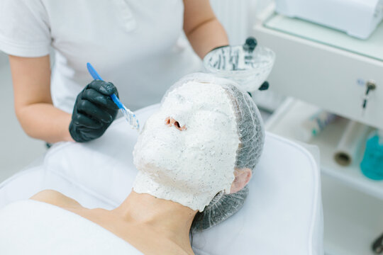 Applying alginate mask with plastic beauty spatula