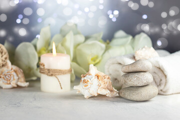 Fototapeta na wymiar massage stones, seashell, burning candles, rolled towels, sea salt, flowers, abstract lights. Spa resort therapy composition