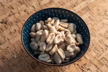blue bowl with unsalted peeled peanuts on cork