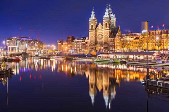Fototapeta Amsterdam, Netherlands city center view with riverboats and the  Basilica of Saint Nicholas