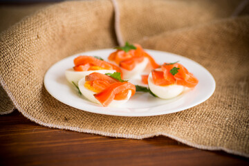 halves of boiled eggs with pieces of salted salmon