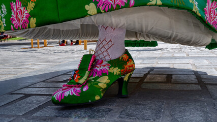 A young girl in festive clothes shows off her beautiful bright shoes in the main square of Valencia, Spain. The Fallas Festival is the most famous Spanish holiday, which is held in March.