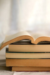 Stack of books. Open book on top. Selective focus.
