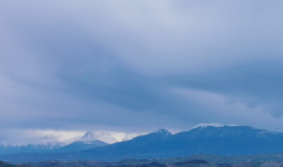 Fototapeta na wymiar Grandi nuvole sulle cime delle montagne appennine