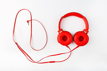 Red round headphones with a cord forming a frame flat lay on a white background with a copy space